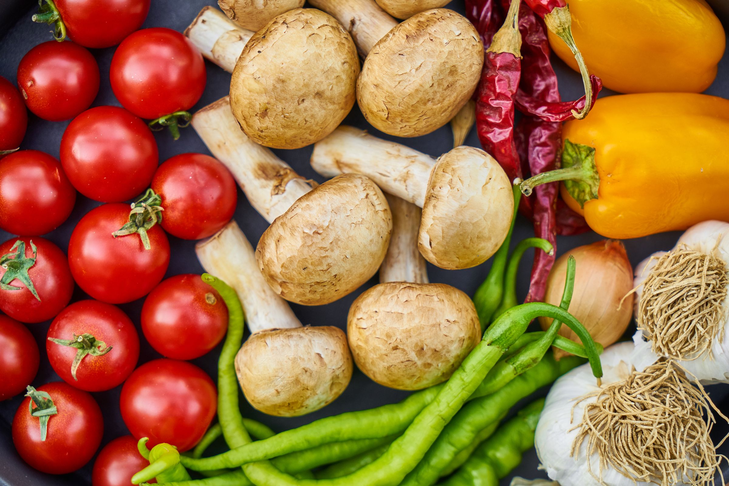 Fresh tomatoes, mushrooms, peppers, beans, onions and garlic arranged together